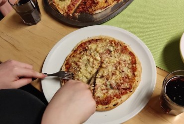 Nuori leikkaaa lautasella olevaa pitsaa.